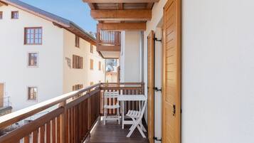 Ein Balkon mit Holzgeländern, einem weißen Tisch und zwei Stühlen.
