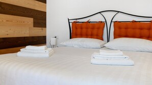 A hotel room with two beds, white bedding, orange headboards, and neatly folded white towels. - Apartment 'Lory' with Mountain View and Balcony (Daldoss)