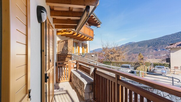 A wooden balcony with a stone wall, a metal railing, and a view of a mountainous landscape. - Apartment 'Lory' with Mountain View and Balcony (Daldoss)