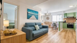 Ein modernes Wohnzimmer mit Sofa, Essbereich und einer Küche mit grünen Schränken, sowie ein Gemälde eines Anlegers.