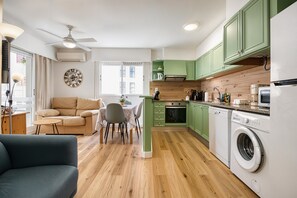 Ein kompakter Wohnraum mit Sofa, Esstisch und Waschmaschine.
