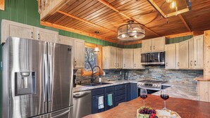 A kitchen with wooden cabinets, a stainless steel refrigerator, a stone backsplash, and a wooden countertop. - Rushmore Retreat - View of Mt Rushmore + Hot Tub + Game Room (Keystone)