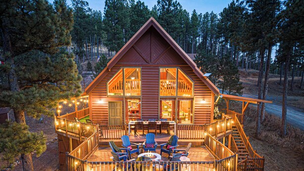 A log cabin with a deck, outdoor seating, and a staircase. - Rushmore Retreat - View of Mt Rushmore + Hot Tub + Game Room (Keystone)