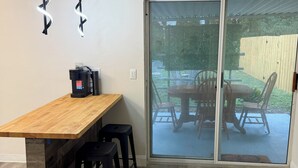 A modern kitchen with a wooden countertop, black bar stools, and pendant lighting. - Sunshine Paradise - Elegant 2-bedroom unit in charming Orange Park, FL (Orange Park)