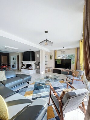 A modern living room with a sofa, chairs, a TV, and a fireplace. - Gite Jade - Four Bedroom House, Sleeps 8 (Samois-sur-Seine)