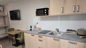 A compact kitchen with a microwave, sink, and a small dining area with a table and chairs. - Razor Vista Apartments in the Soča Valley - STUDIO (Tolmin)