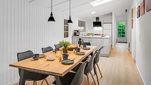 A modern kitchen with white cabinetry, a wooden dining table, and black pendant lights. - "Mena" - 10km from the sea by Interhome (Oksbøl)