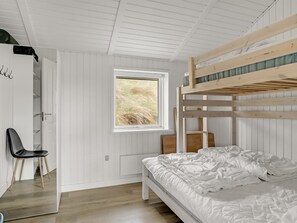A bedroom with a bunk bed, a chair, a window with a view of grass, and white walls. - "Nimrod" - 70m from the sea by Interhome (Thisted)