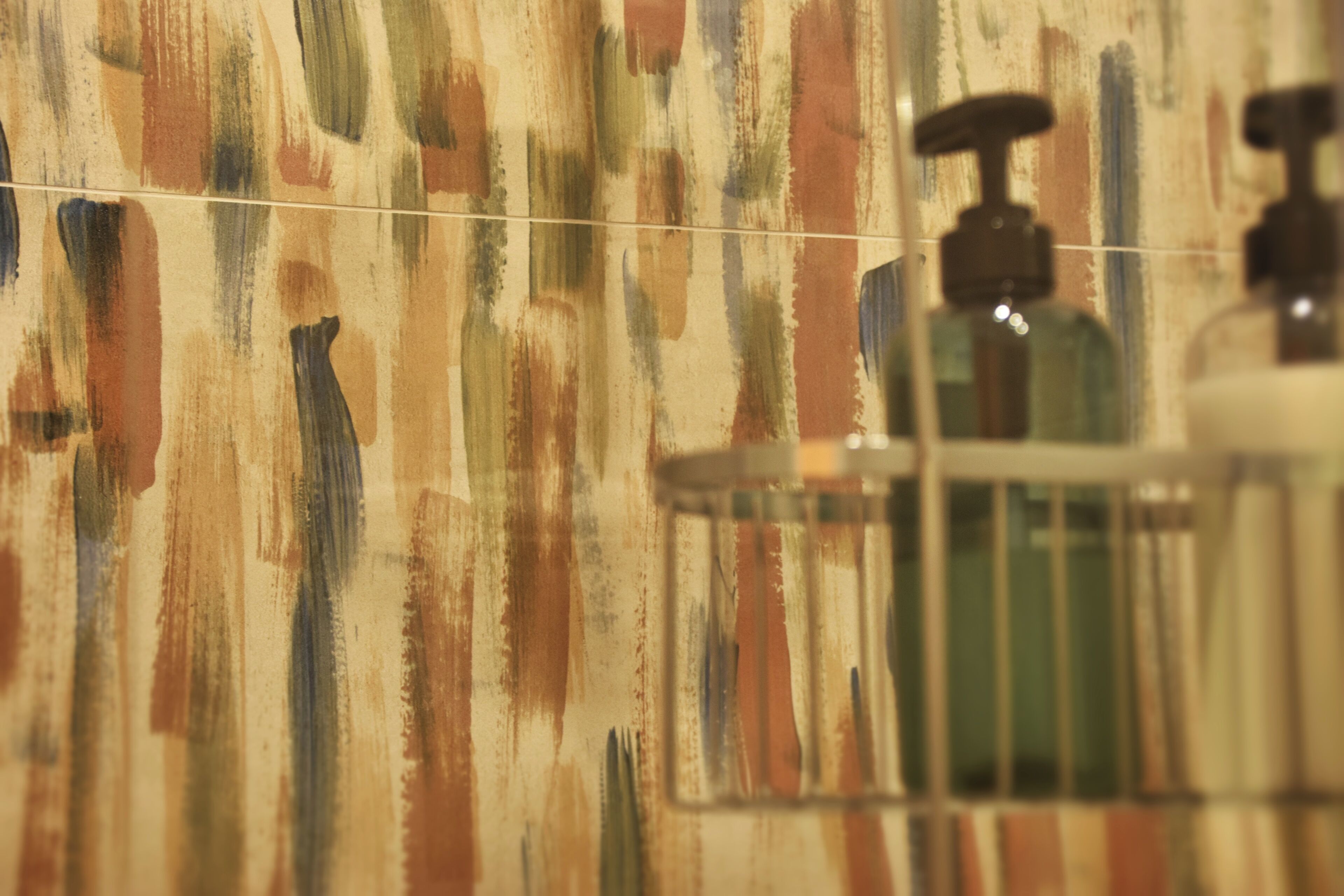 A bathroom with a textured wall and a hand soap dispenser.
