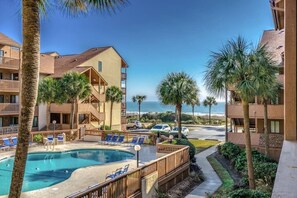 A hotel with a pool, palm trees, and a view of the ocean. - Two bedroom steps from the beach fully updated! (Myrtle Beach)