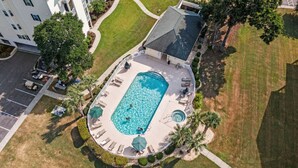 An aerial view of a swimming pool surrounded by lounge chairs and palm trees, with a building in the background. - 3bedroom condo in Ocean Keyes, North Myrtle (North Myrtle Beach)