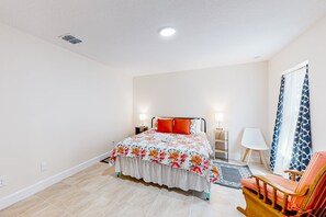 A bedroom with a bed, bedside tables, a chair, and a window with curtains. - Tropical Haven Retreat (Palm Bay)