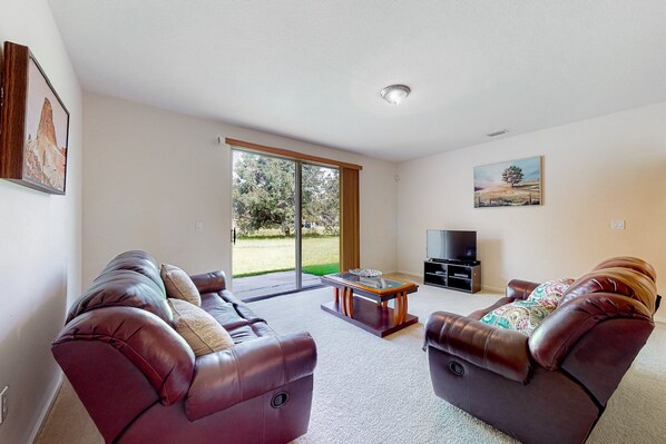 A living room with two leather sofas, a coffee table, and a TV stand. - Palm Bay Cove (Palm Bay)