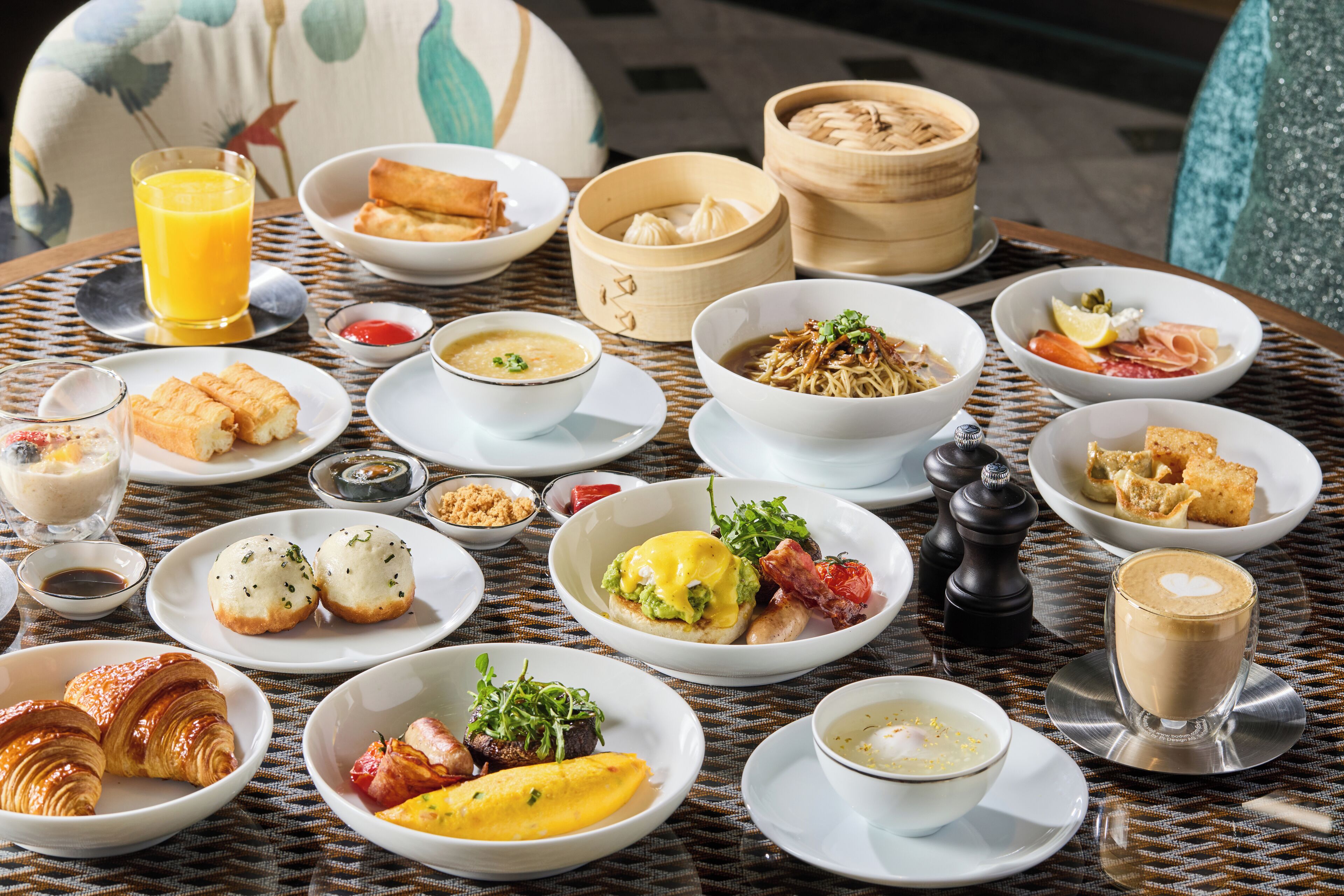 A table set with various breakfast dishes including eggs, pastries, and beverages.