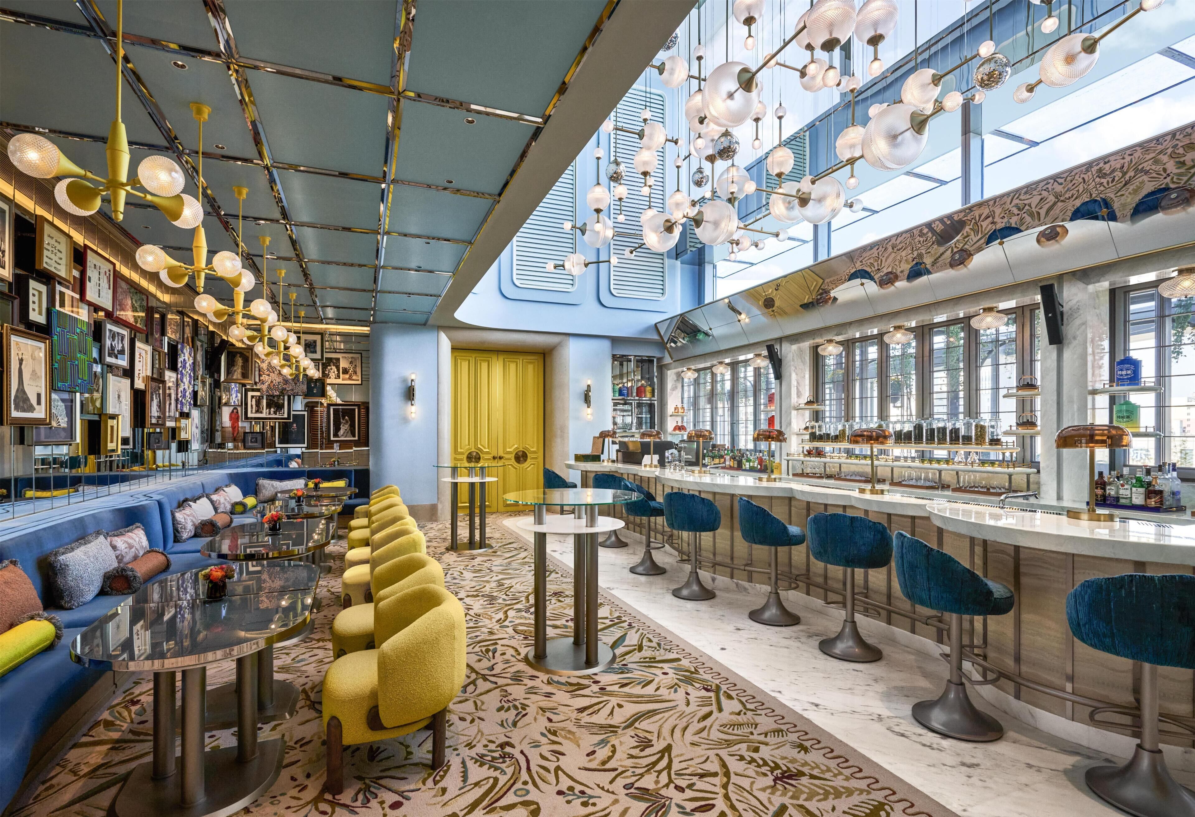 Un espace bar doté d’un long comptoir, de nombreux tabourets et d’un coin salon avec des canapés et des fauteuils.