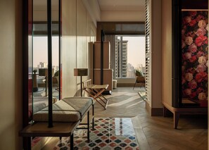 Una habitación de hotel moderna con un ventanal grande, un sofá, una mesita y un detalle decorativo en la pared.