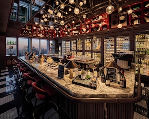 A bar with a city view, red shelves, and a marble counter.