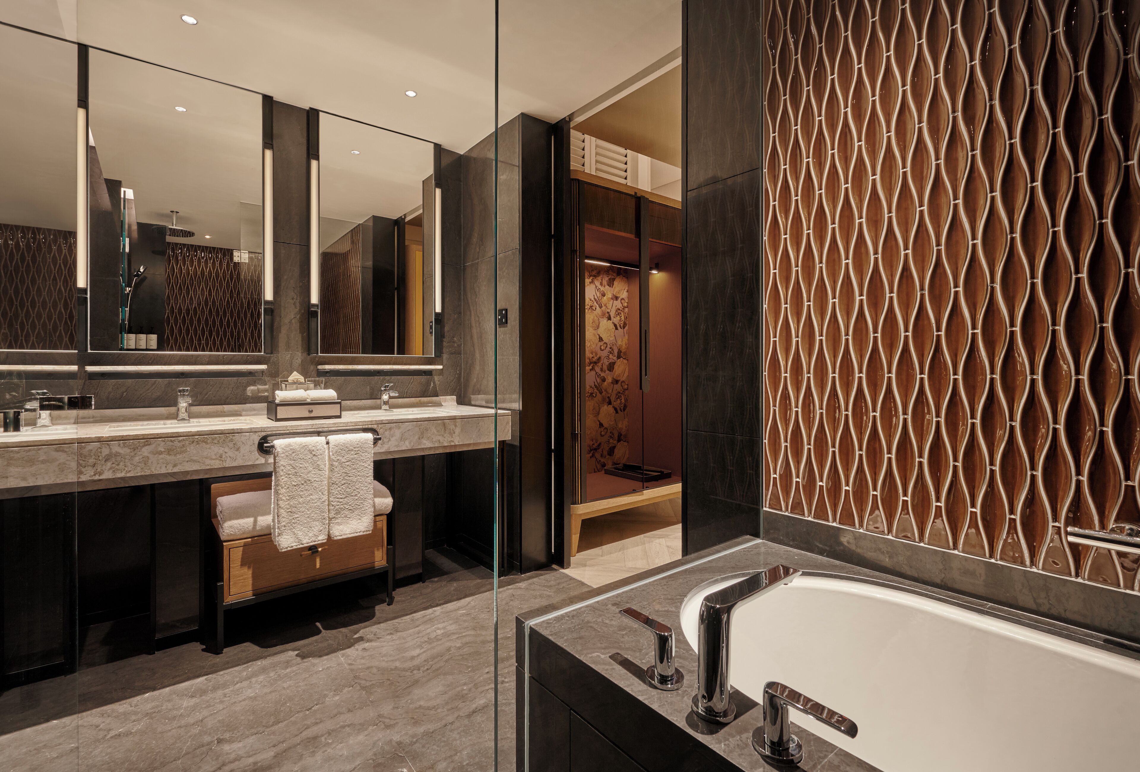 Un baño moderno con un espejo grande, lavamanos doble y bañera.