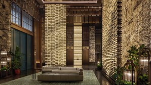 A lobby with a modern sofa, patterned wall, and potted plants. - Andaz Shanghai ITC (Shanghai)