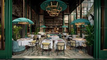A restaurant with round tables, chairs, and a chandelier.