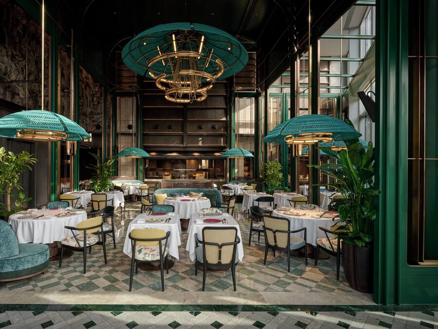A restaurant with round tables, chairs, and a chandelier.