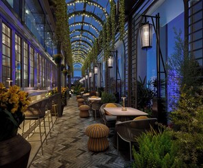 An indoor garden with tables and chairs, a wooden floor, and hanging plants. - Andaz Shanghai ITC (Shanghai)