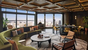 A modern hotel lobby with a green sofa, round coffee table, and yellow chairs. - Andaz Shanghai ITC (Shanghai)