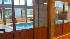 Ein großzügiger Innenbereich mit großen Fenstern, die einen Pool und die Außenanlage zeigen.