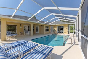 Ein überdachter Pool mit Liegestühlen, einer Terrasse und freiem Blick zum Himmel.