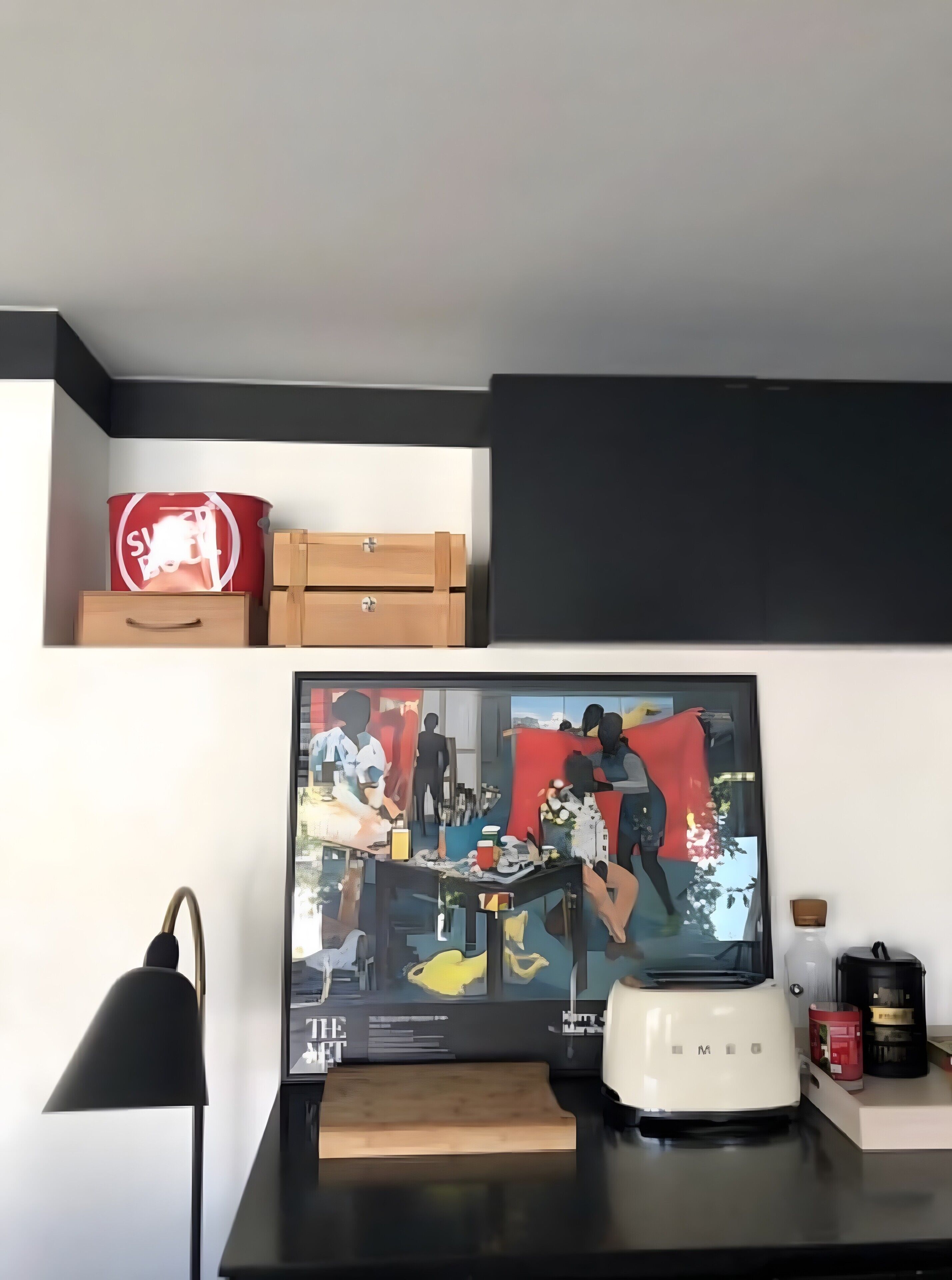 Een keukenhoek met een televisie, een koffiezetapparaat en een blender op het aanrecht.