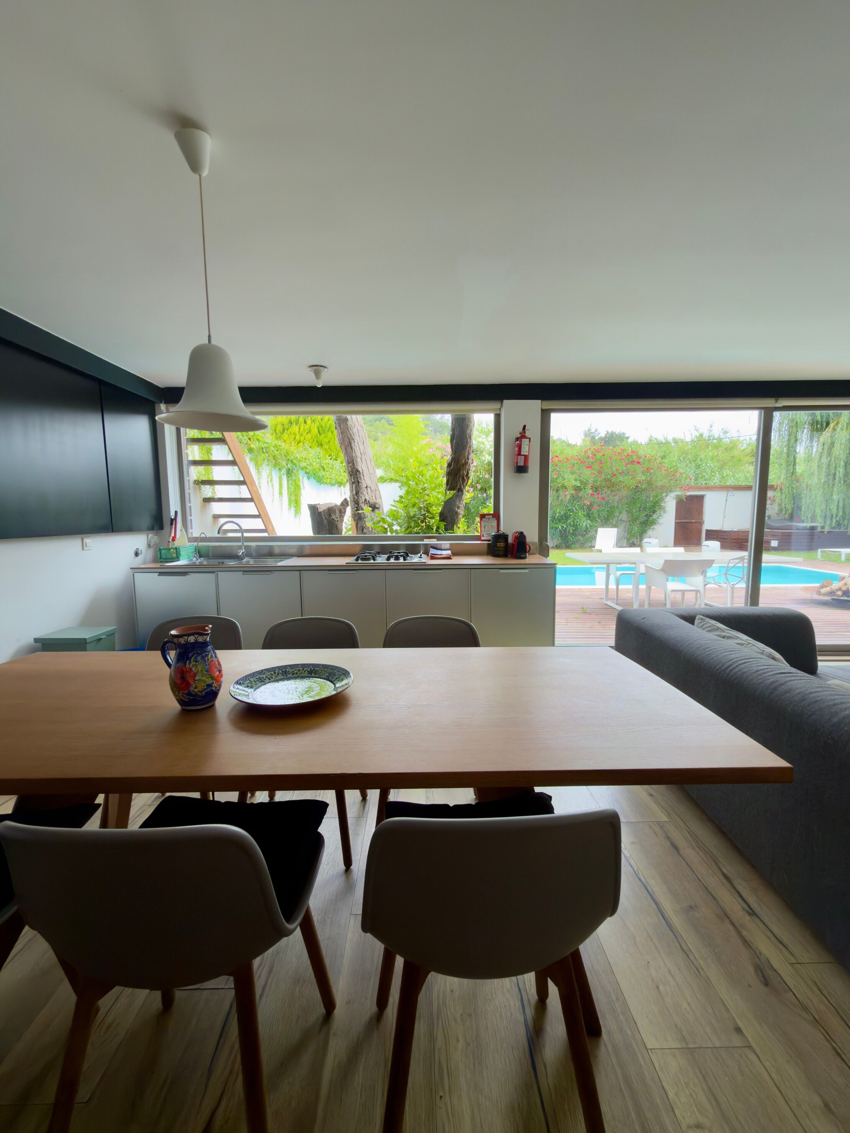 Una cocina moderna con comedor, ventanas amplias y vista a una piscina.