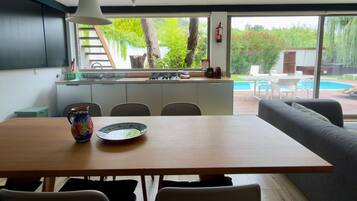 Una cocina moderna con comedor, ventanas amplias y vista a una piscina.