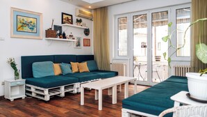 Uma sala de estar moderna com um sofá verde-turquesa, mesa de centro branca e piso de madeira.