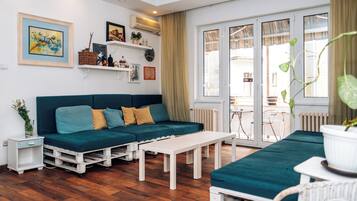 Un salon moderne avec un canapé de couleur turquoise, une table basse blanche et un parquet en bois.