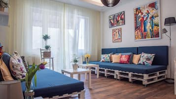 Un salon chaleureux avec un canapé bleu, une table basse en bois et une petite table sur laquelle est posé un vase de fleurs.