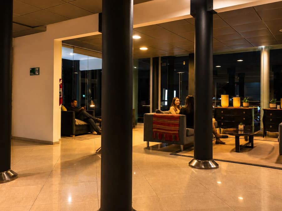 A lobby area with seating arrangements, a reception desk, and a glass partition.