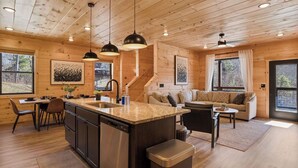 A wooden cabin interior with a kitchen, dining area, and living room. - NEW! Indoor Pool Retreat - Sugar Maple Splash w/ Hot Tub (Sevierville)