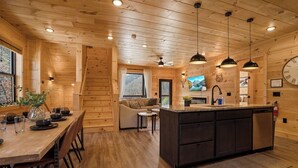 A wooden cabin interior with a dining area, kitchen, and living space. - NEW! Indoor Pool Retreat - Sugar Maple Splash w/ Hot Tub (Sevierville)