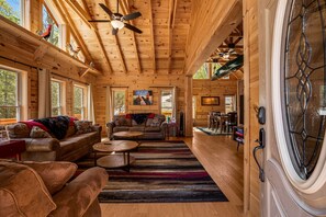 A log cabin interior with a wooden ceiling, a dining area, and a living room with sofas and a coffee table. - Modern Asheville Cabin | Quiet & Peaceful Retreat (Fairview)