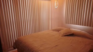A bedroom with a large bed, two pillows, and a decorative wall piece. - Alojamiento Olsi (Torreón)