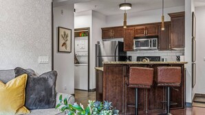 A modern kitchen with dark wooden cabinets, stainless steel appliances, and a bar area with stools. - Amazing Views 1BR Condo w/ Hot Tub + Pool! (Canmore)