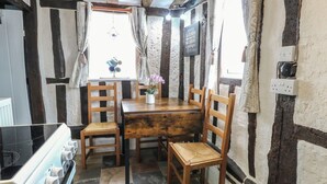 A rustic kitchen with a wooden table, four wooden chairs, a stove, and stone tiles. - Driftway Stables Retreat (Diss)