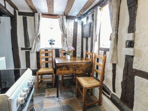 A rustic kitchen with a wooden table, four wooden chairs, a stove, and stone tiles. - Driftway Stables Retreat (Diss)