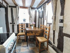 Una cocina rústica con una mesa de madera, cuatro sillas de madera, una estufa y baldosas de piedra.