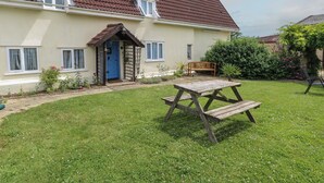 A house with a sloped roof, a front porch, a wooden bench, and a small garden.