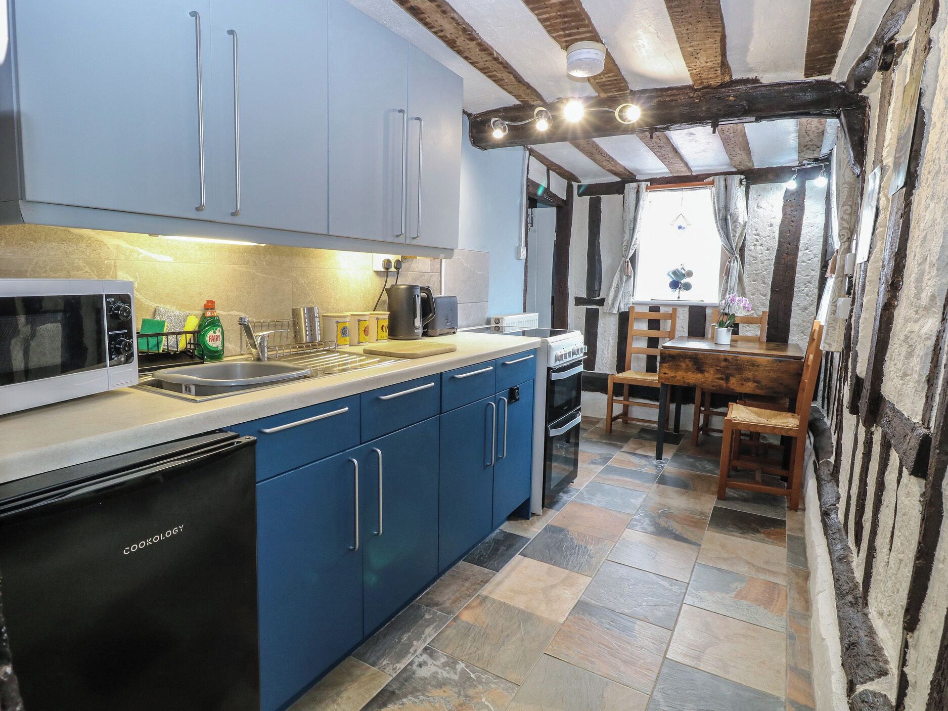 A kitchen with blue cabinets, a microwave, a coffee maker, and a stove.