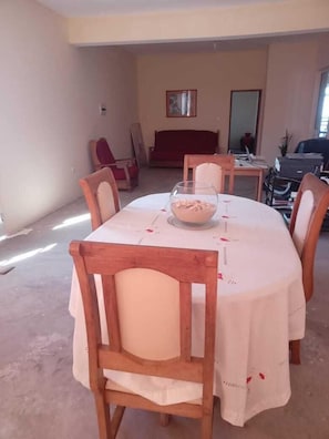 Un comedor con una mesa redonda cubierta por un mantel blanco, rodeado de sillas de madera.