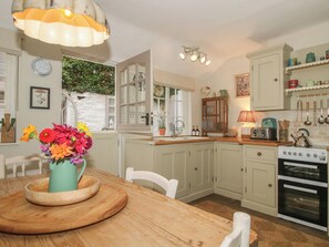 Une cuisine avec une table en bois, un vase de fleurs et une cuisinière.