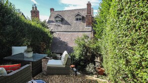 A garden with a stone house, outdoor furniture, and a variety of plants. - 8 Welsh Street (Bishops Castle)