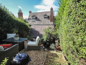 A garden with a stone house, outdoor furniture, and a variety of plants. - 8 Welsh Street (Bishops Castle)